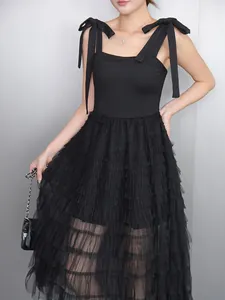 Detail of black tiered mesh camisole dress featuring elegant bow straps and A-line silhouette