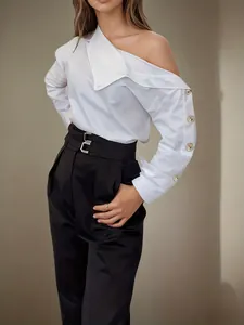 Close-up detail of white off-the-shoulder blouse featuring decorative gold sleeve buttons