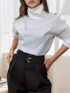 Elegant white high-neck blouse with decorative gold buttons on shoulders in a minimalist setting.