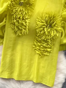 Close-up detail of elegant lime green chiffon blouse with 3D floral applique and rhinestones