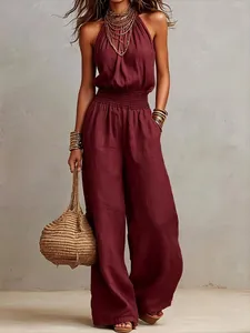 Elegant sleeveless linen backless wide leg jumpsuit in burgundy with straw bag