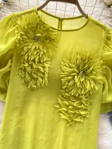 Close-up of elegant lime green chiffon blouse with 3D flower appliqué and rhinestones