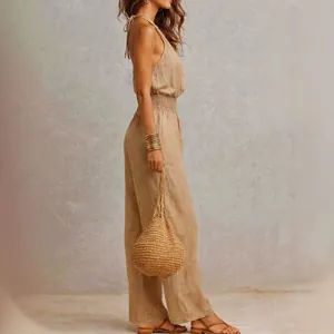 Side view of a khaki sleeveless linen backless jumpsuit with gathered waist detail
