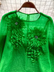 Close-up of vibrant green chiffon blouse with 3D floral appliques and rhinestones