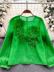 Detail view of green sheer blouse with large 3D floral appliqués and lantern sleeves