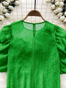 Detail view of green semi-transparent chiffon blouse with elegant lantern sleeves and neckline.