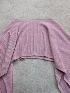 Primo piano dettagliato che mostra la trama del tessuto a coste di un crop top rosa a spalle scoperte