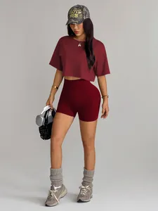 Trendy dark red seamless high waist gym shorts and crop top set worn by an athletic model