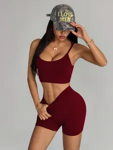 Fit woman in burgundy high-waist yoga shorts and camisole bra set with camo cap