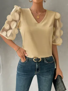 Detail of sheer bubble sleeves with 3D applique polka dots on beige V-neck blouse.