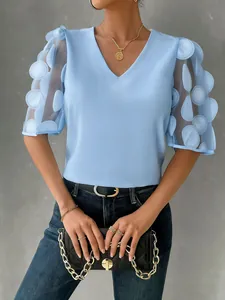 Close-up detail of a light blue V-neck blouse featuring sheer 3D dot puff sleeves