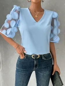 Detail view of a light blue V-neck blouse featuring 3D floral sheer puff sleeves.