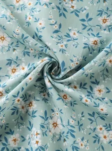 Close-up view of mint green fabric with delicate white and blue floral print patterns.