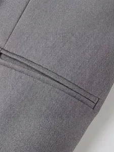 Primer plano del tejido gris texturizado y bolsillo de ojal en un chaleco minimalista