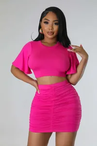 Detail view of pink two-piece set featuring a ruffled crop top and ruched skirt