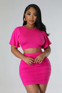 Hot pink two-piece outfit featuring a ruffled crop top and a ruched bodycon skirt