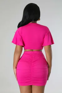 Back view of hot pink two-piece set featuring flutter sleeve crop top and ruched skirt