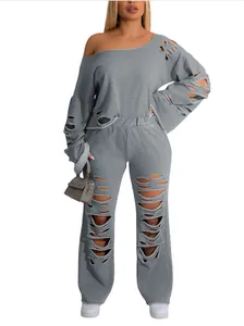 Detail of a gray ripped two-piece set with off-shoulder sweatshirt and matching pants.