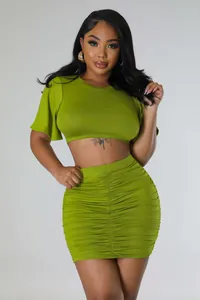 Vibrant olive green two-piece outfit featuring a crop top and ruched bodycon mini skirt.