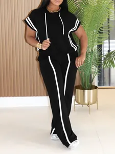 Detail view of women's black two-piece hooded tracksuit set with white side stripes