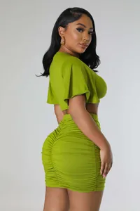 Detail side view of olive green two-piece set featuring crop top and ruched mini skirt