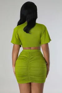 Back view of fashionable two-piece green ruched skirt and short crop top set for women.
