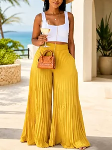 Detail showing the drape of yellow pleated wide-leg pants in a tropical resort context