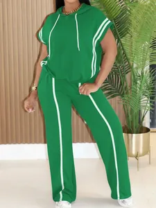 Woman wearing stylish green sports two-piece set with white stripes and hooded top