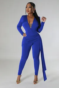 Full view of a sexy deep V-neck blue jumpsuit with draped side detail and long sleeves.