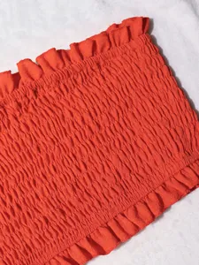 Vista detallada del tejido elástico nido de abeja y volantes del top bandeau naranja