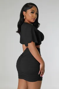 Side view of black two-piece set featuring short crop top and ruched mini skirt