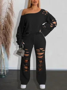 Close-up detail of black distressed two-piece set featuring ripped off-shoulder top and pants