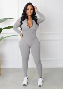 Full body view of a woman wearing a grey ribbed sports jumpsuit with front zipper