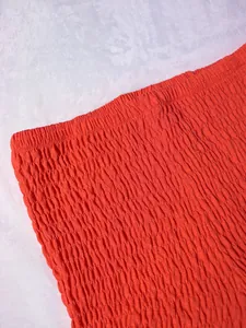 Primer plano detallado del top palabra de honor fruncido naranja con textura elástica