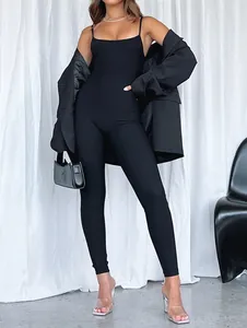 Detail view of a chic black backless jumpsuit styled with an oversized blazer and heels