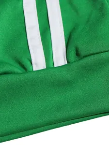 Macro detail showing white double stripes on green sporty fabric for women's tracksuit.