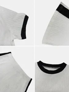 Close-up macro shot of pleated fabric texture on white top with black contrast trim detail.