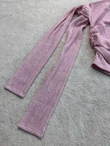 Dettaglio ravvicinato del tessuto increspato rosa di un elegante top con spalle scoperte