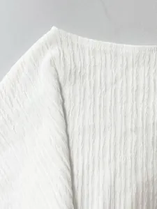 Primo piano del tessuto plissettato bianco che mostra i dettagli della trama ruvida.