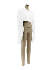 Detailed view of white shirt with dramatic puffy shoulders and asymmetric hem on mannequin