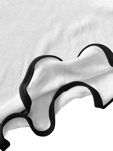 Close-up detail of white ribbed summer dress featuring a black wavy lettuce edge hemline