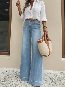 Woman wearing vintage washed light blue wide-leg jeans with a white shirt and belt.