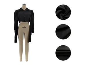 Detailed view of black cropped shirt with structured puff shoulders and fabric macro.