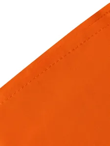 Gros plan sur un tissu plissé orange vif montrant les coutures et la texture fine.