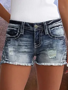 Gedetailleerd beeld van dames denim shorts met gaten, onafgewerkte zoom en contraststiksels