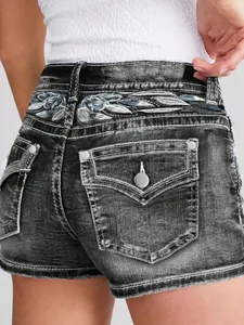 Detalle de pantalones cortos vaqueros negros con intrincado bordado floral en cintura