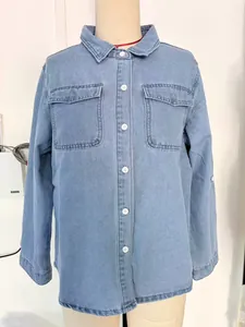 Front detail of a women's blue denim shirt with white buttons and pockets on mannequin