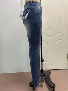 Side view of blue stretch denim jeans with wing embroidery on back pocket.