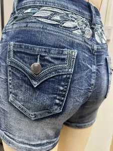Macro que muestra el detalle del bordado de hojas plateadas y el bolsillo de los shorts