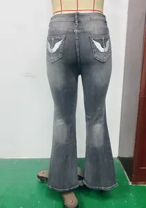 Rear view of washed grey flared jeans with silver wing embroidery on back pockets